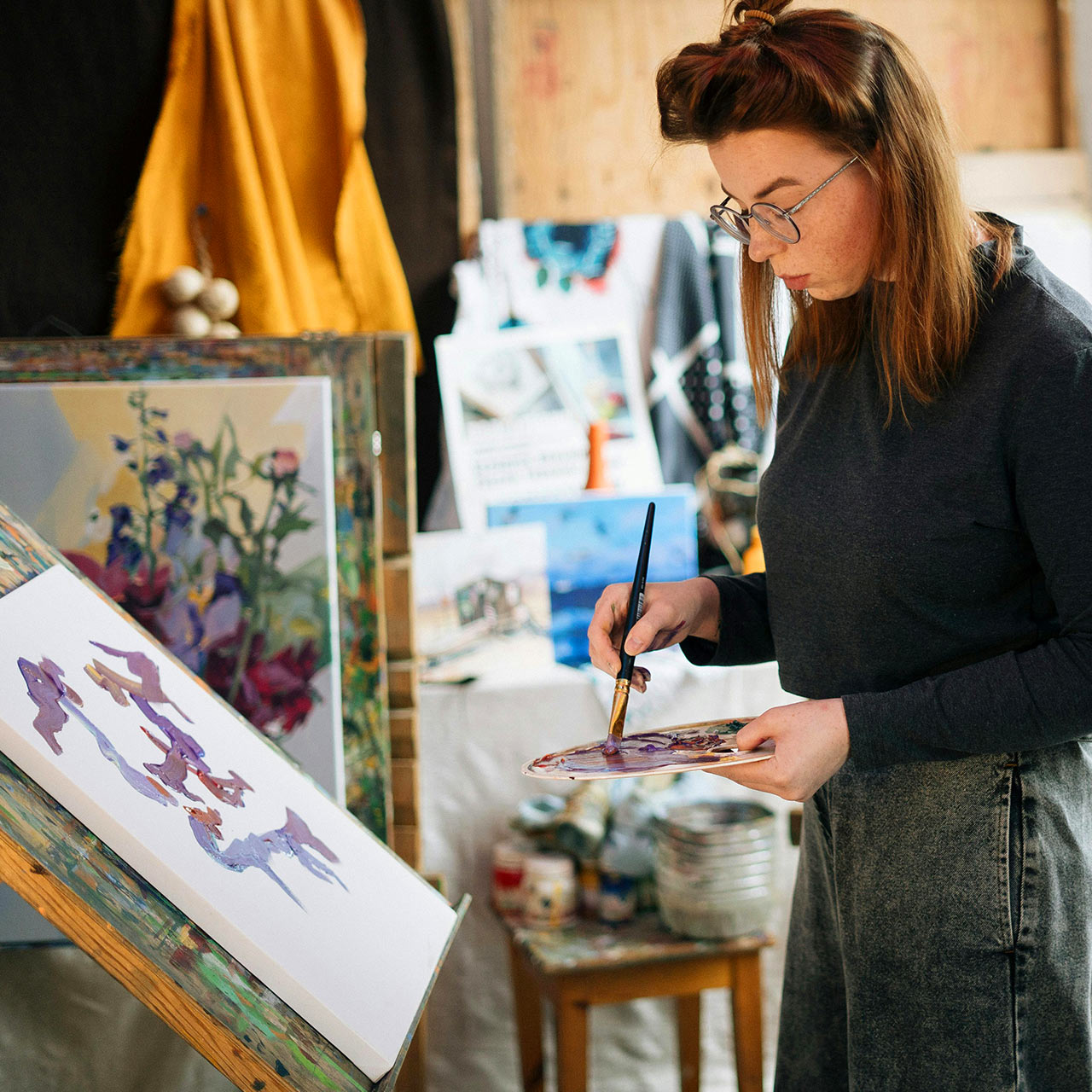 A woman mixing purple purple paint in her studio