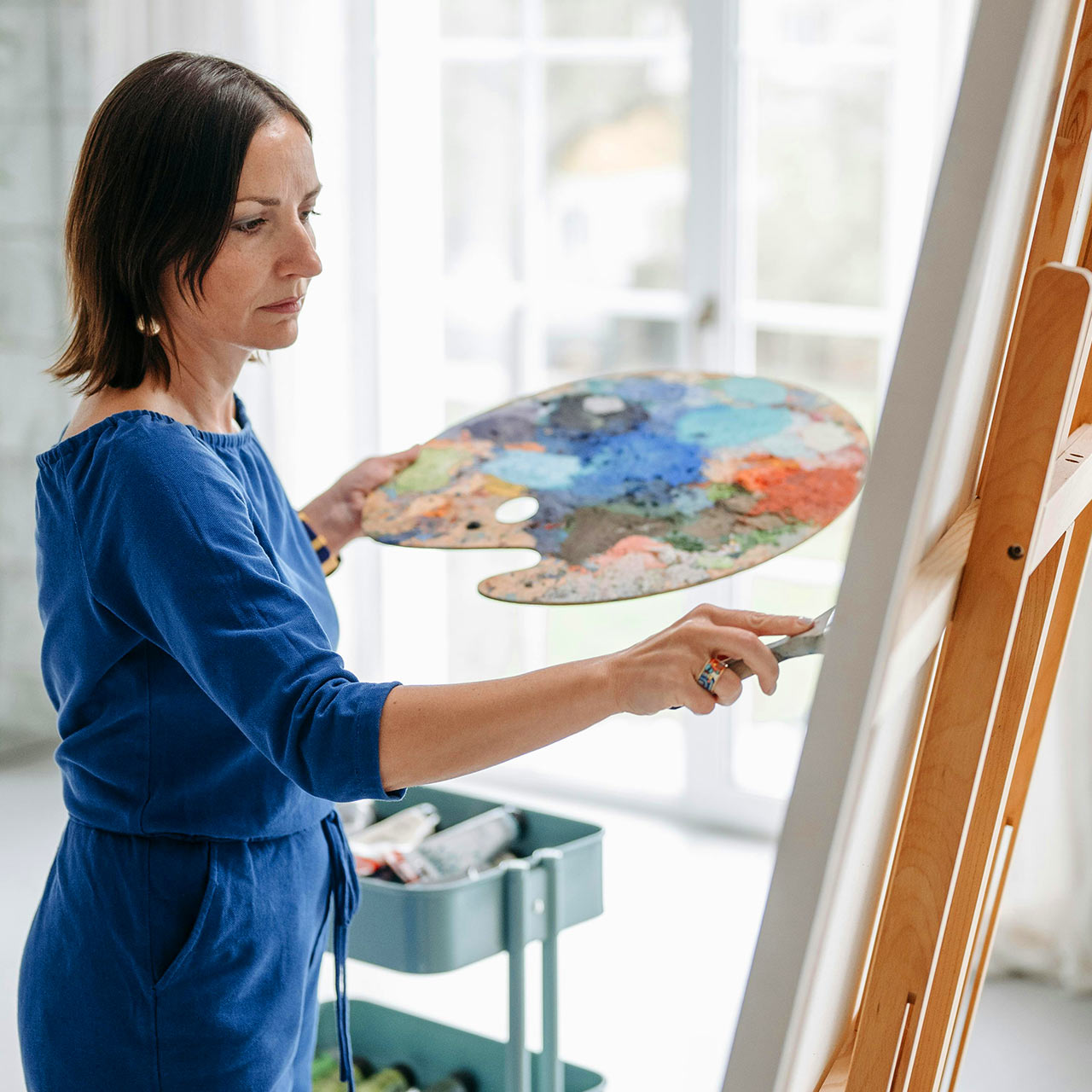 A woman painting stood at an easel, painting