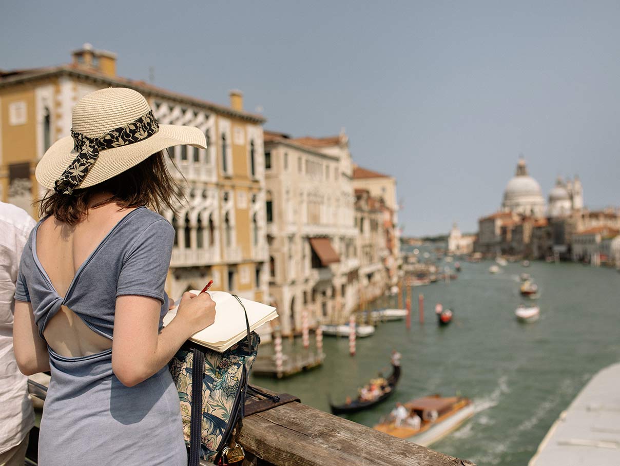 a lady stood won the Rialto bridge, sketching a sc